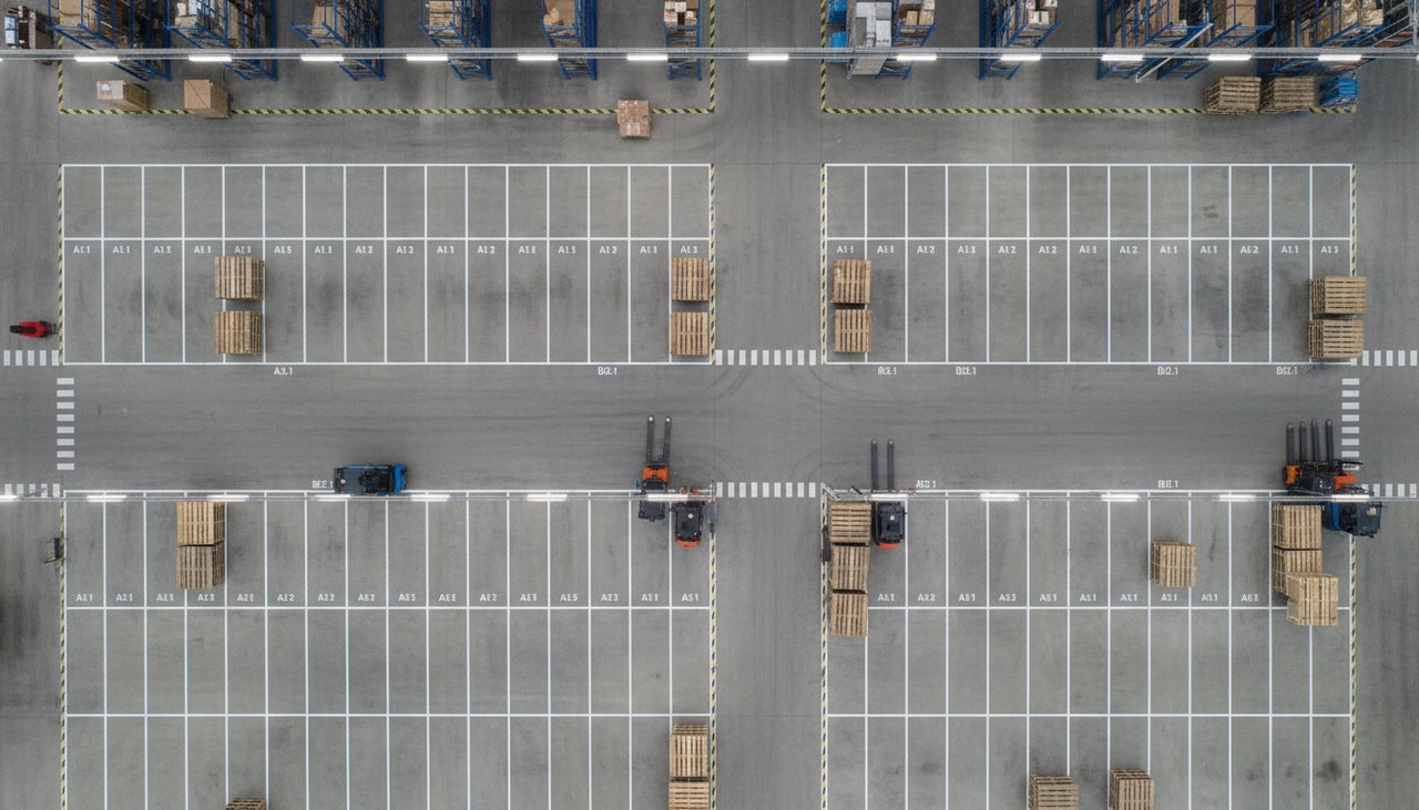 Zone de stockage délimitée par un marquage au sol blanc dans un atelier industriel