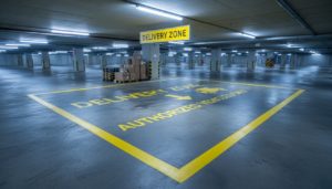 Marquage au sol jaune d'une zone de livraison dans un parking souterrain de centre commercial