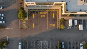 Zone de livraison marquée en jaune sur une voie urbaine, avec panneau réglementaire, vue en plongée